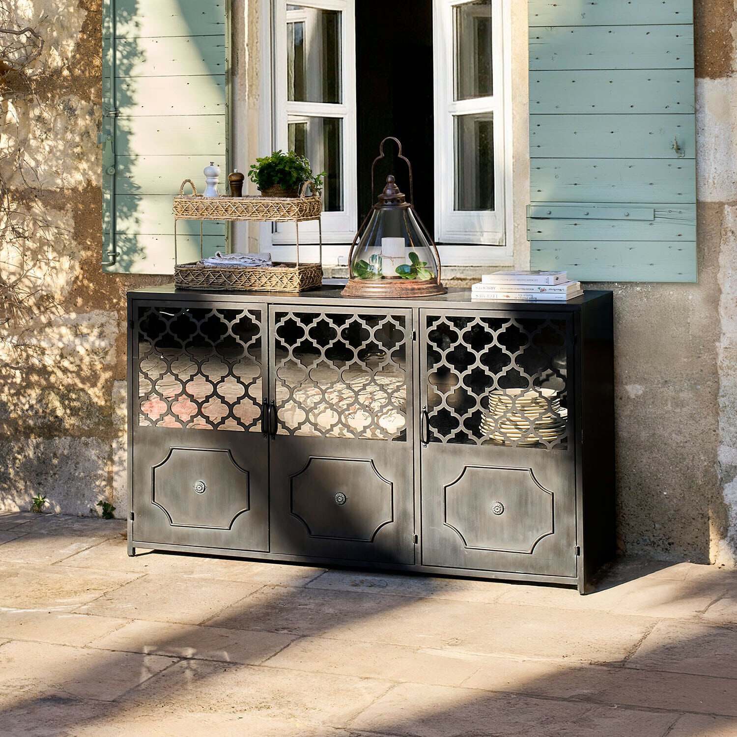 Sideboard Astralon Schwarzes Metall-Sideboard mit filigranen Türen auf Terrasse vor Fenster mit grünen Fensterläden