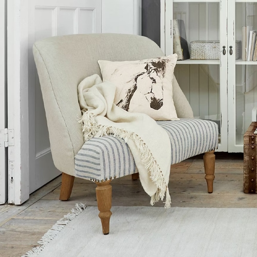 Zweisitziges Sofa mit gestreiftem Stoffbezug und beigem Rücken, Holzbeinen, Kissen und Decke