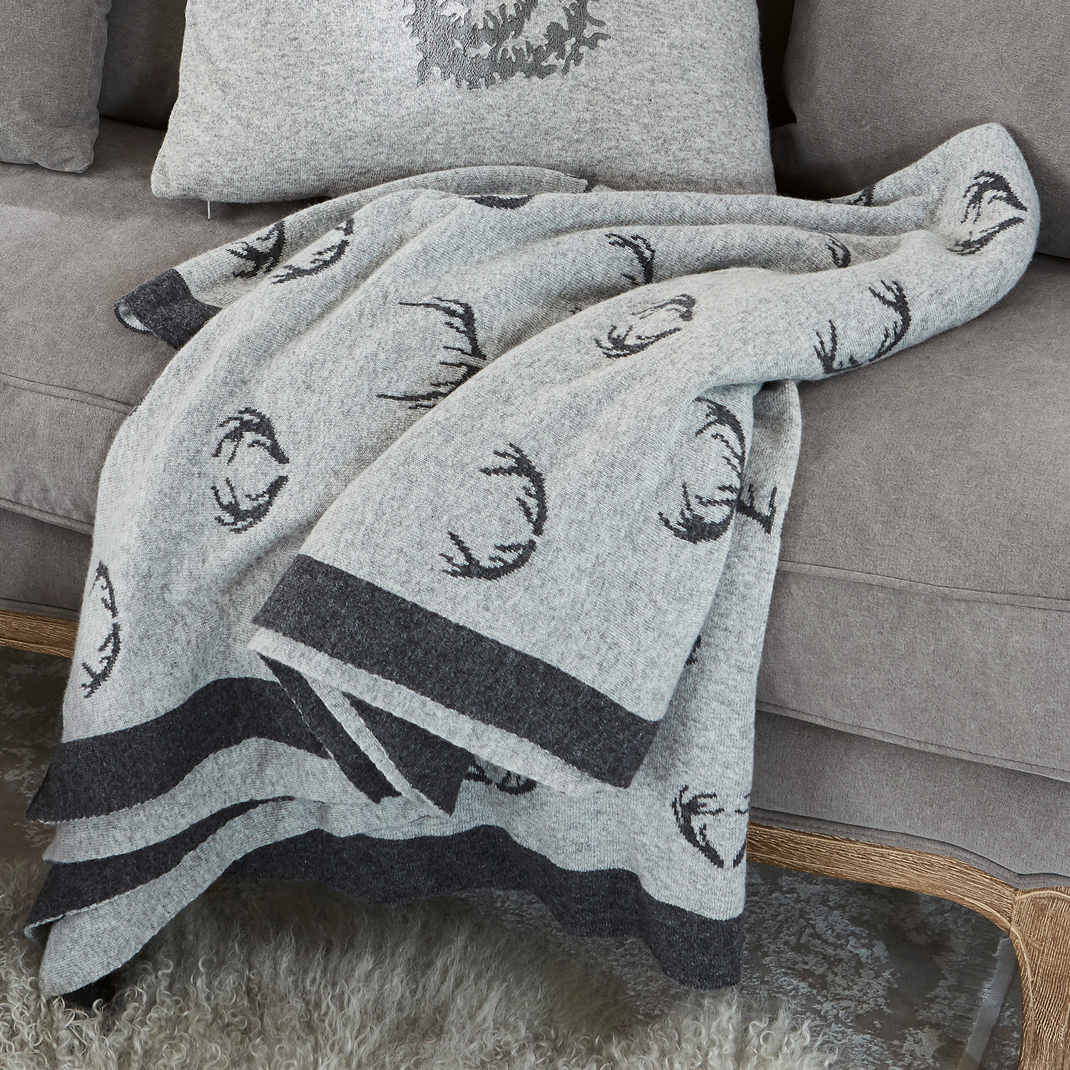 Wendedecke Lodge Graue Wolldecke mit schwarzem Hirschgeweihmuster auf grauem Sofa, gemütliche Wohnraumdekoration