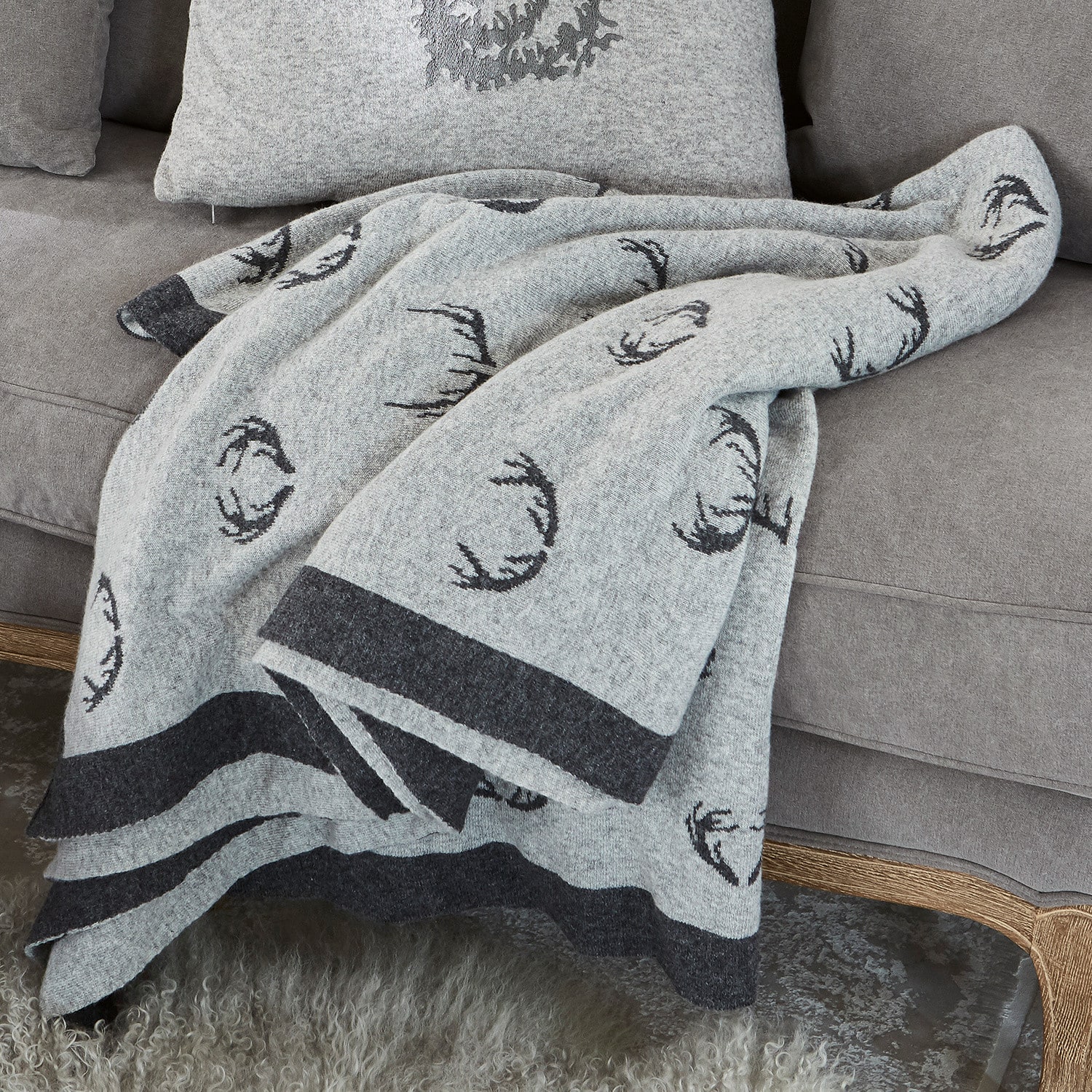 Wendedecke Lodge Graue Wolldecke mit schwarzem Hirschgeweihmuster auf grauem Sofa, gemütliche Wohnraumdekoration