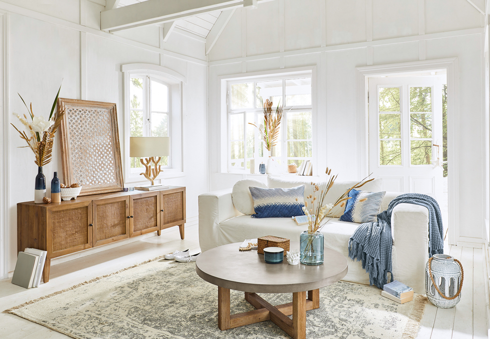 Helles Wohnzimmer im maritimen Stil mit weissem Sofa, Holzkommode und blauen Akzenten