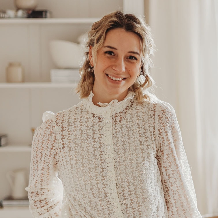 Frau in weisser Spitzenbluse mit Blumenmuster in hellem Wohnraum
