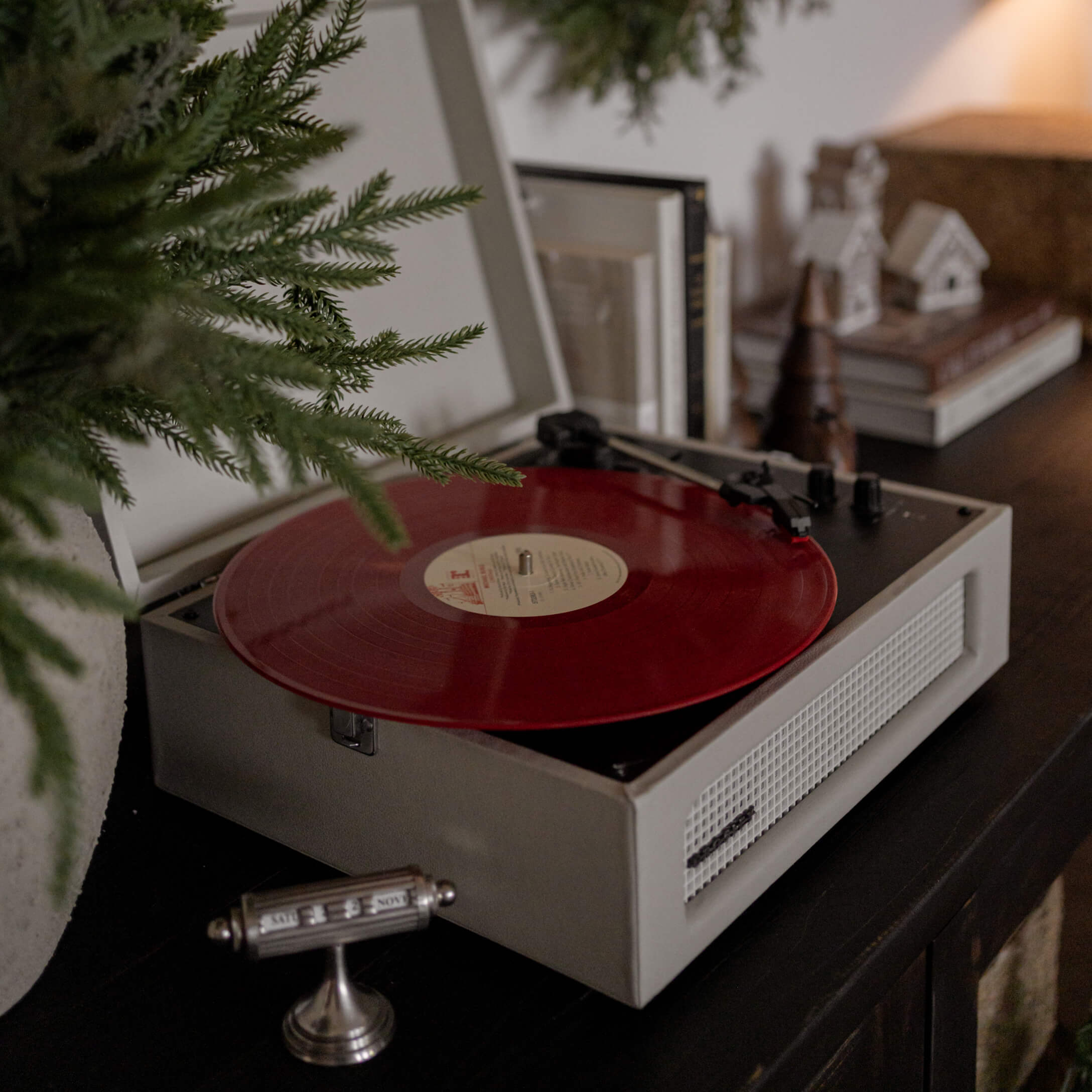 Retro Plattenspieler mit roter Vinylplatte auf dunklem Möbel in gemütlichem Raum