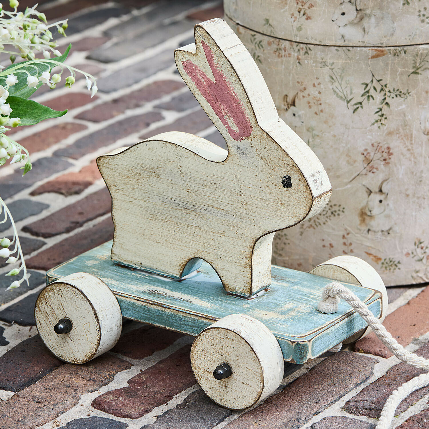 Ziehfigur Moiraine Holzspielzeug Hase in Weiss auf blauer Plattform mit Rädern und Zugseil, nostalgischer Stil