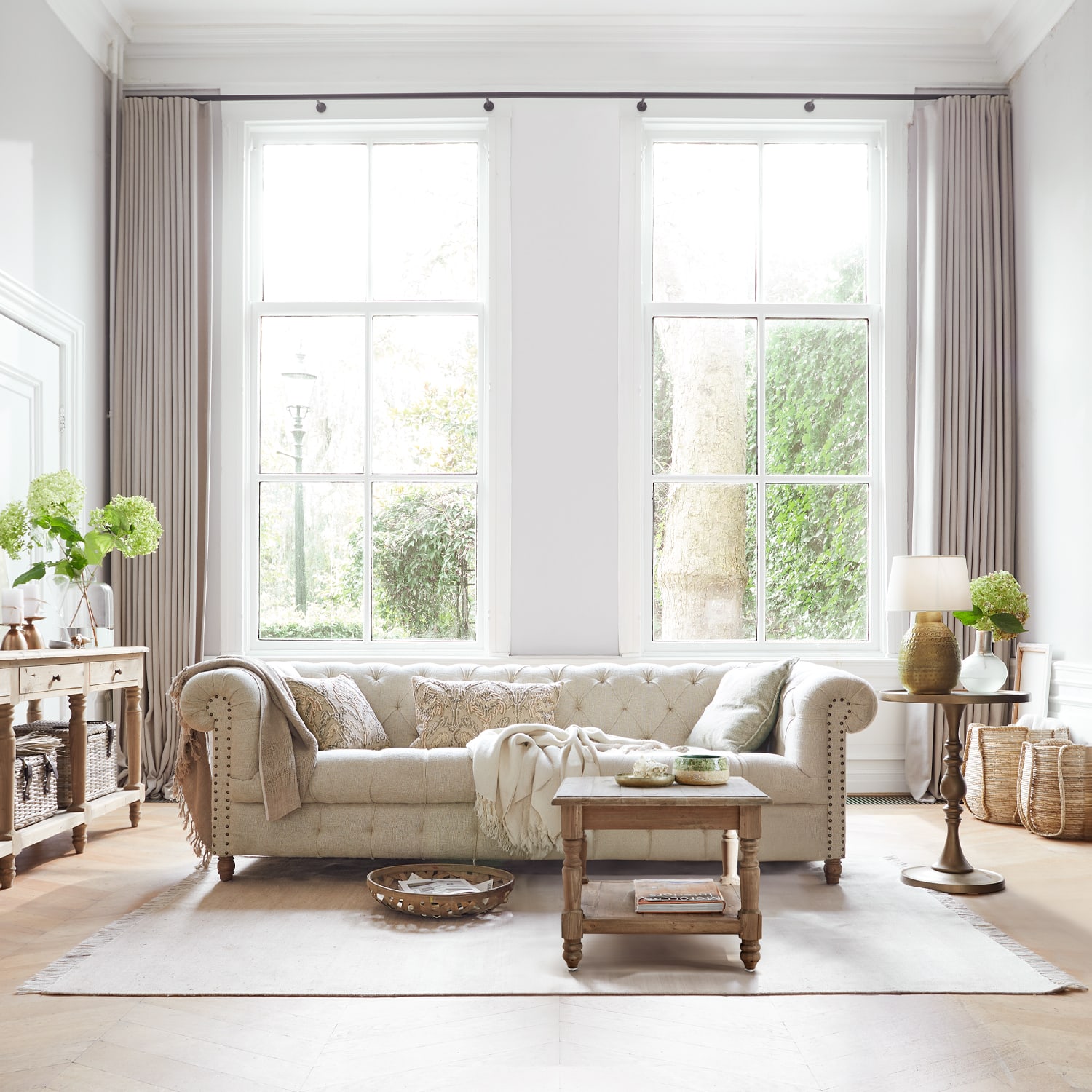Beige gepolstertes Stoffsofa in hellem Wohnzimmer mit Holztisch und Dekorationen