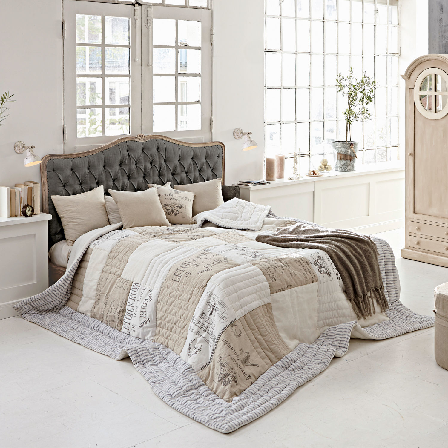 Bett Declaire Gemütliches Schlafzimmer mit Bett und grauem, gepolstertem Kopfteil sowie beige-weisser Vintage-Steppdecke