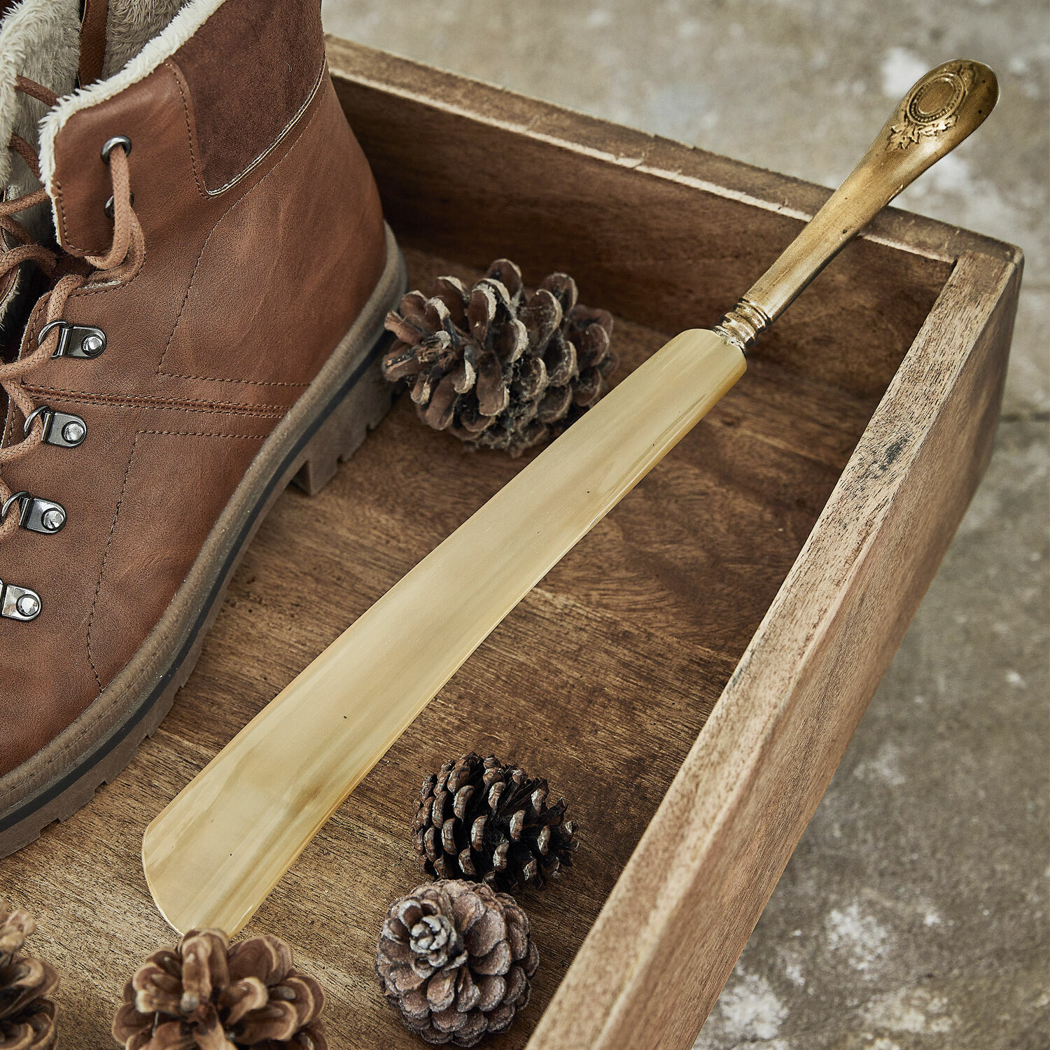 Schuhlöffel Charles Eleganter Schuhanzieher aus hellem Holz mit Messinggriff auf Holztablett neben braunem Schuh.