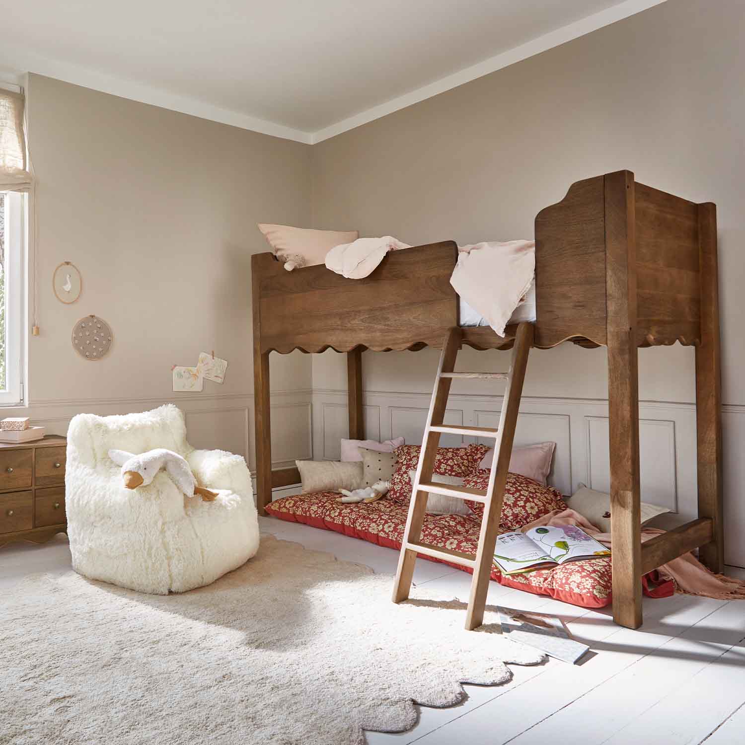Hochbett aus Holz in Naturfarbe mit weichen Kissen und Leiter in hellem Kinderzimmer
