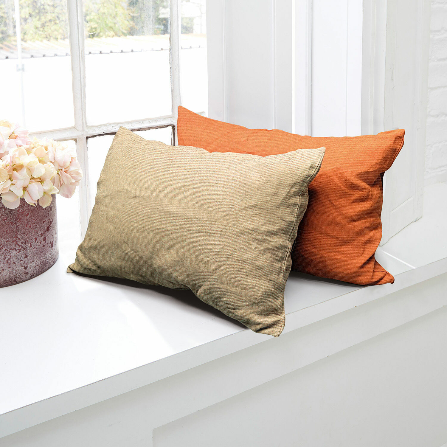 Kissenhülle 2er Set Balesta Zwei dekorative Kissen aus Stoff in Beige und Orange auf weissem Fensterbrett