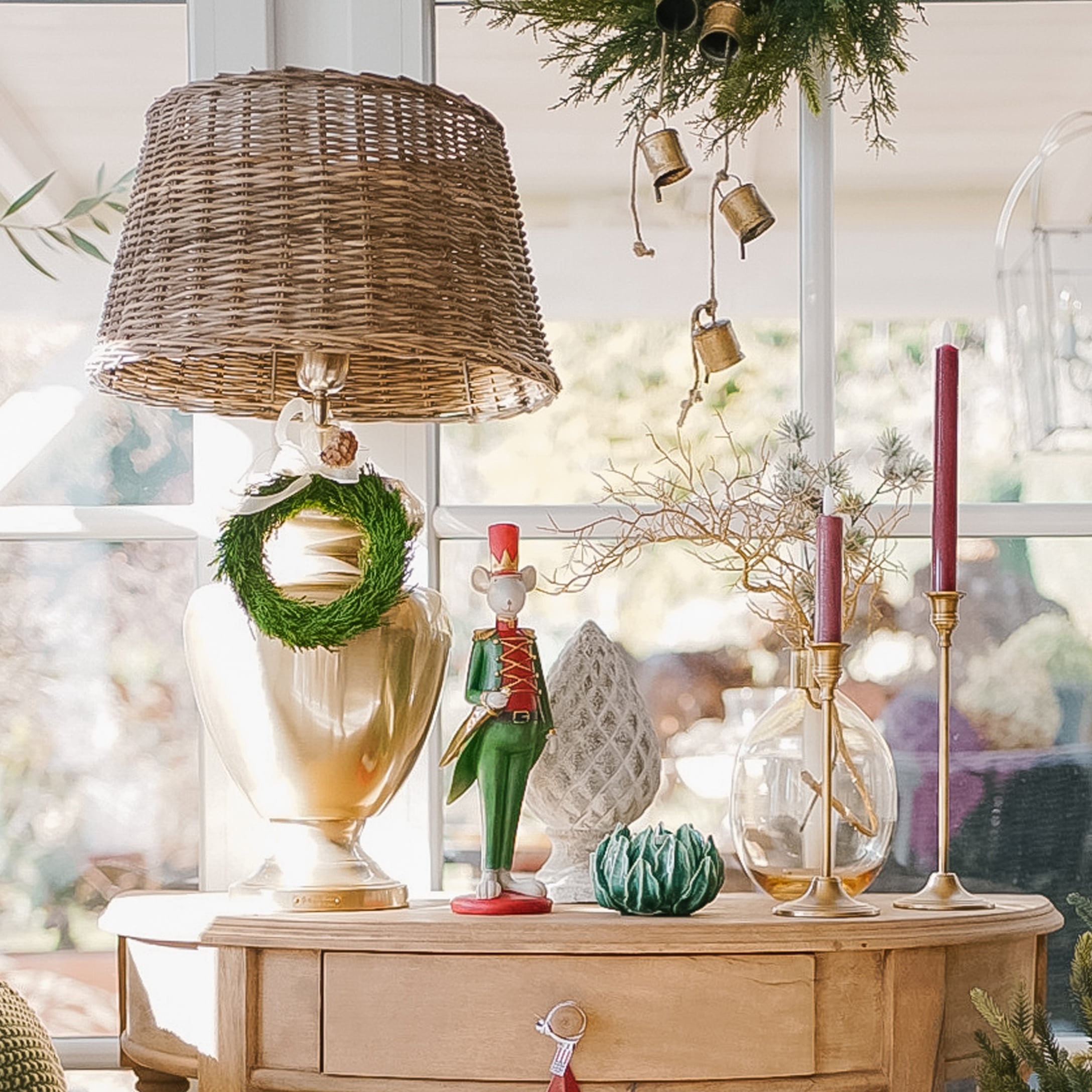 Dekorative Lampe mit Korbgeflechtschirm und Weihnachtsdekoration auf hellem Holztisch im sonnigen Raum