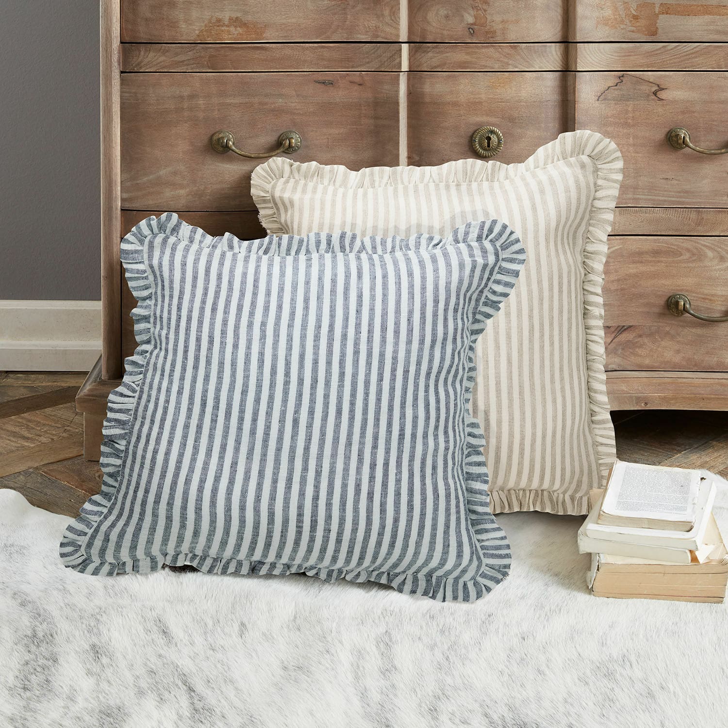 Kissenhülle 2er Set Brenda Zwei dekorative Kissen mit Streifen und Rüschen in Beige und Blau auf dem Teppich vor einer Holzkommode