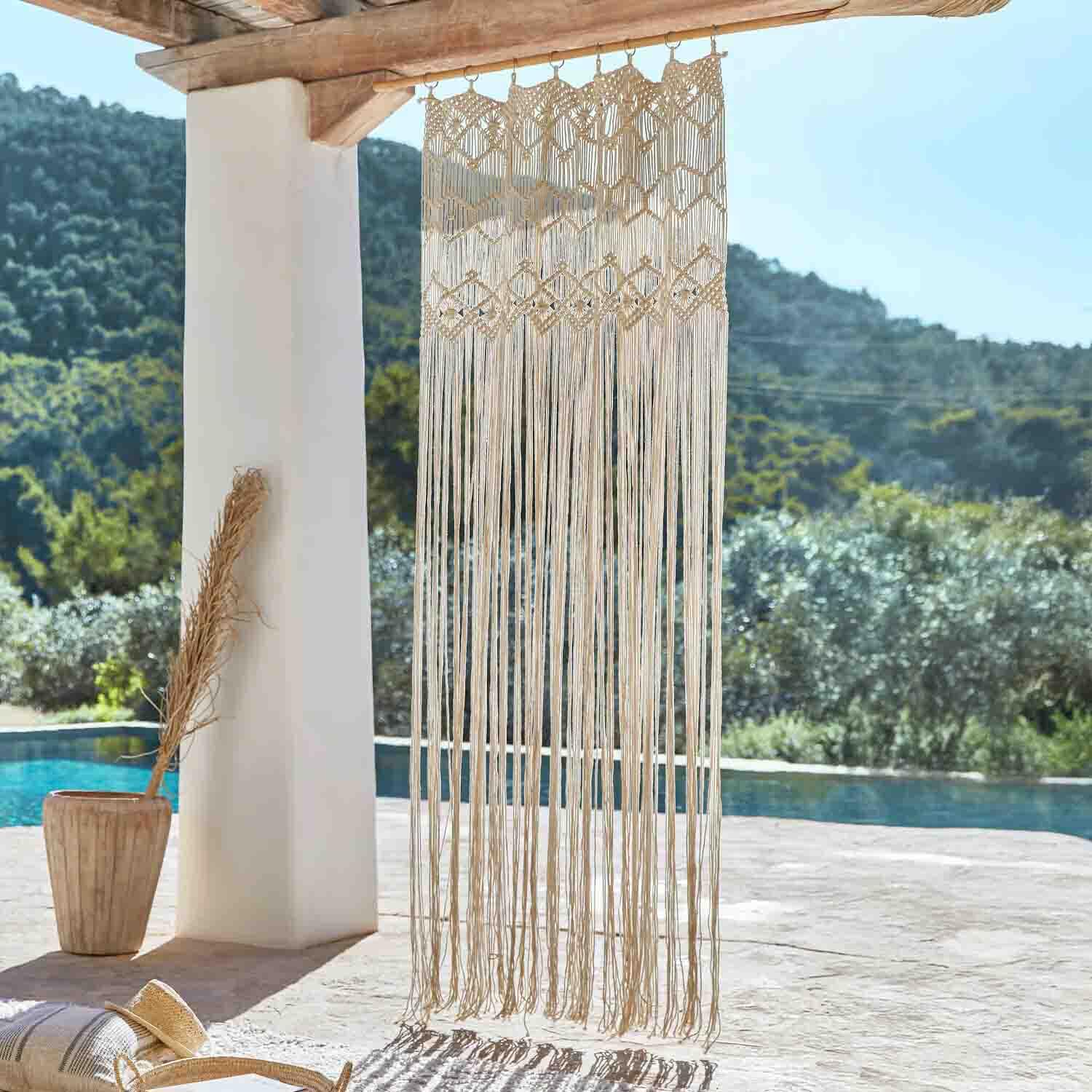 Beige Baumwoll-Makramee an Holzbalken hängend, Boho-Dekoration auf Terrasse mit Poolblick