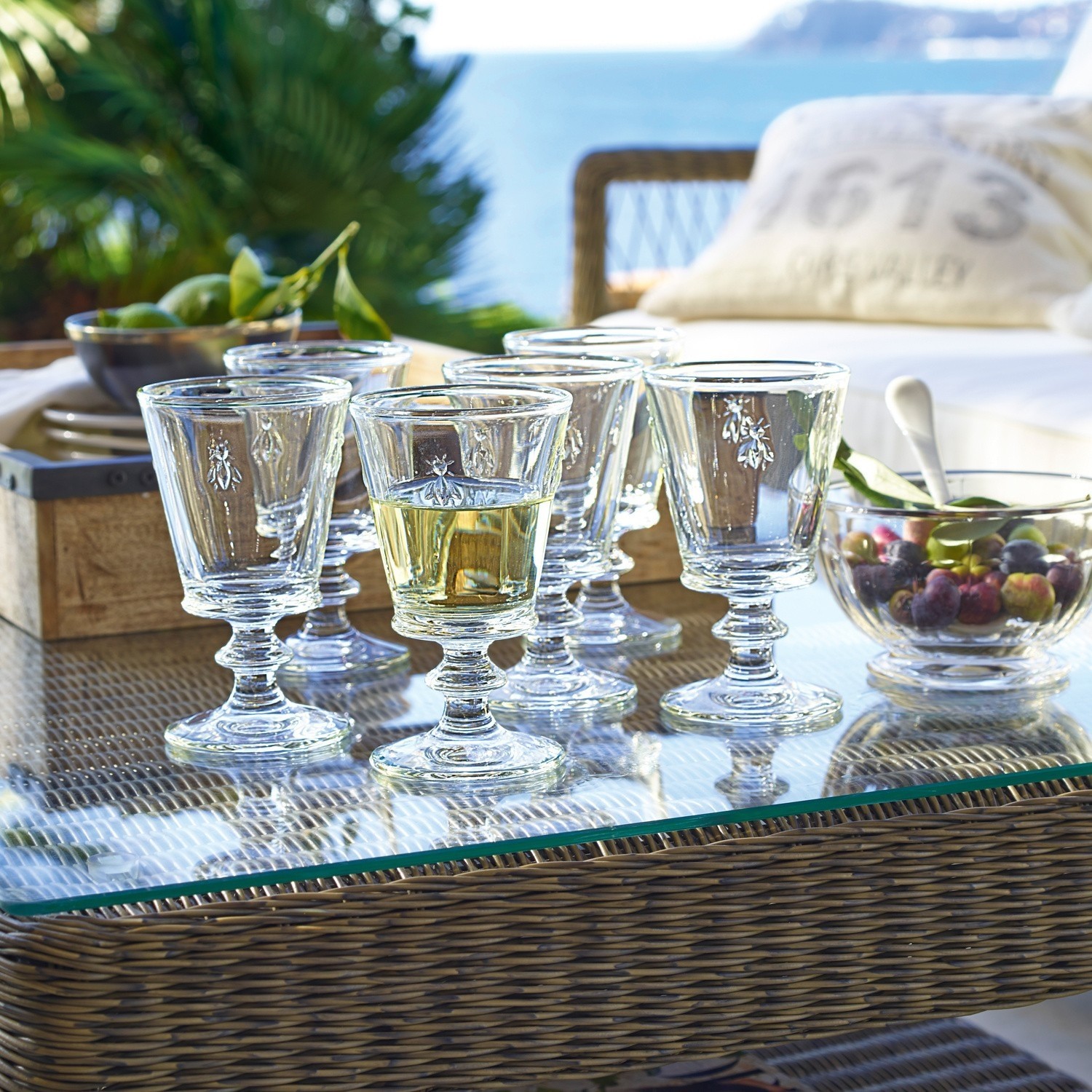 Weingläser 6er Set Puttigny Sechsteiliges Set Gläser aus Glas mit Insektenmotiv auf Glastisch auf Terrasse mit Meerblick
