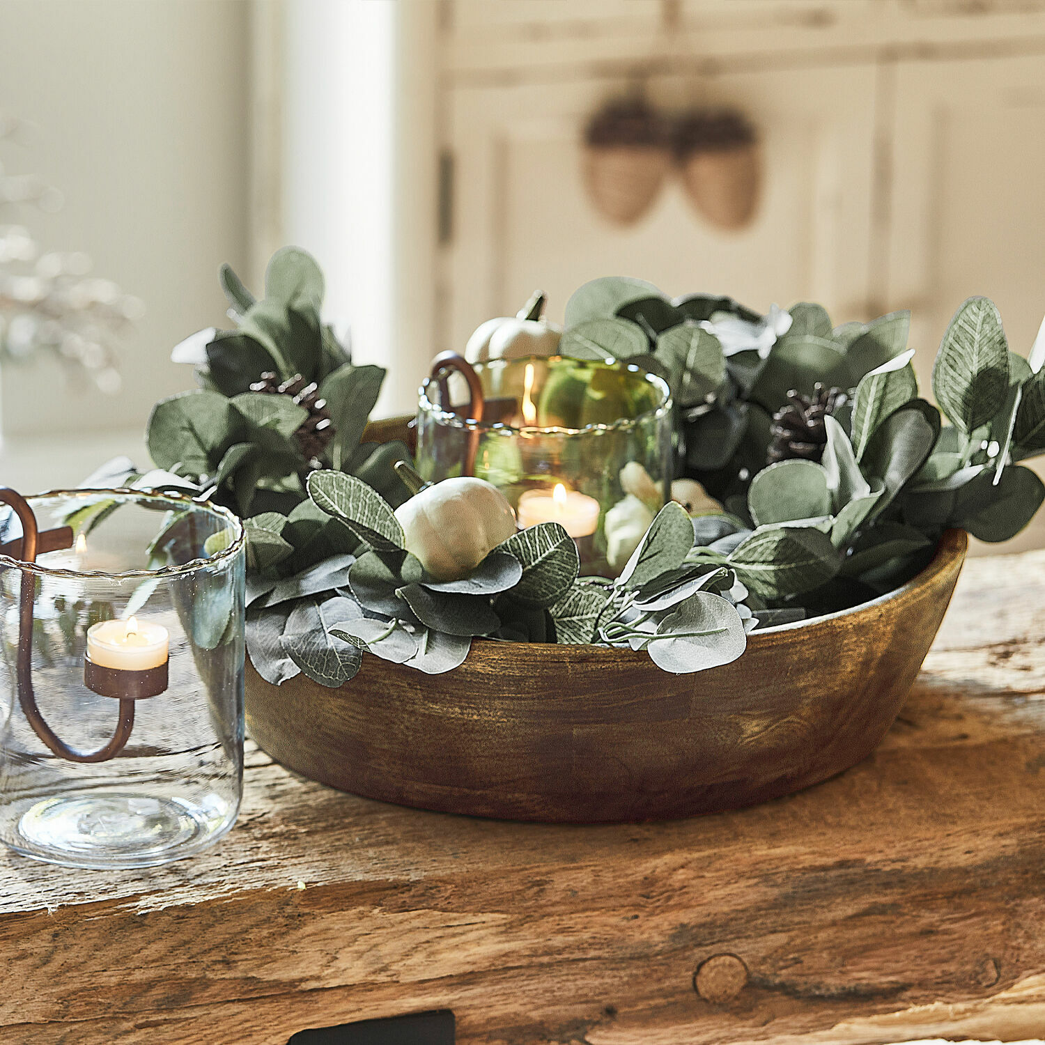 Girlande Belfays Dekorative Holzschale mit grünen Blättern und Kerzen in Glaswindlichtern auf Holztisch