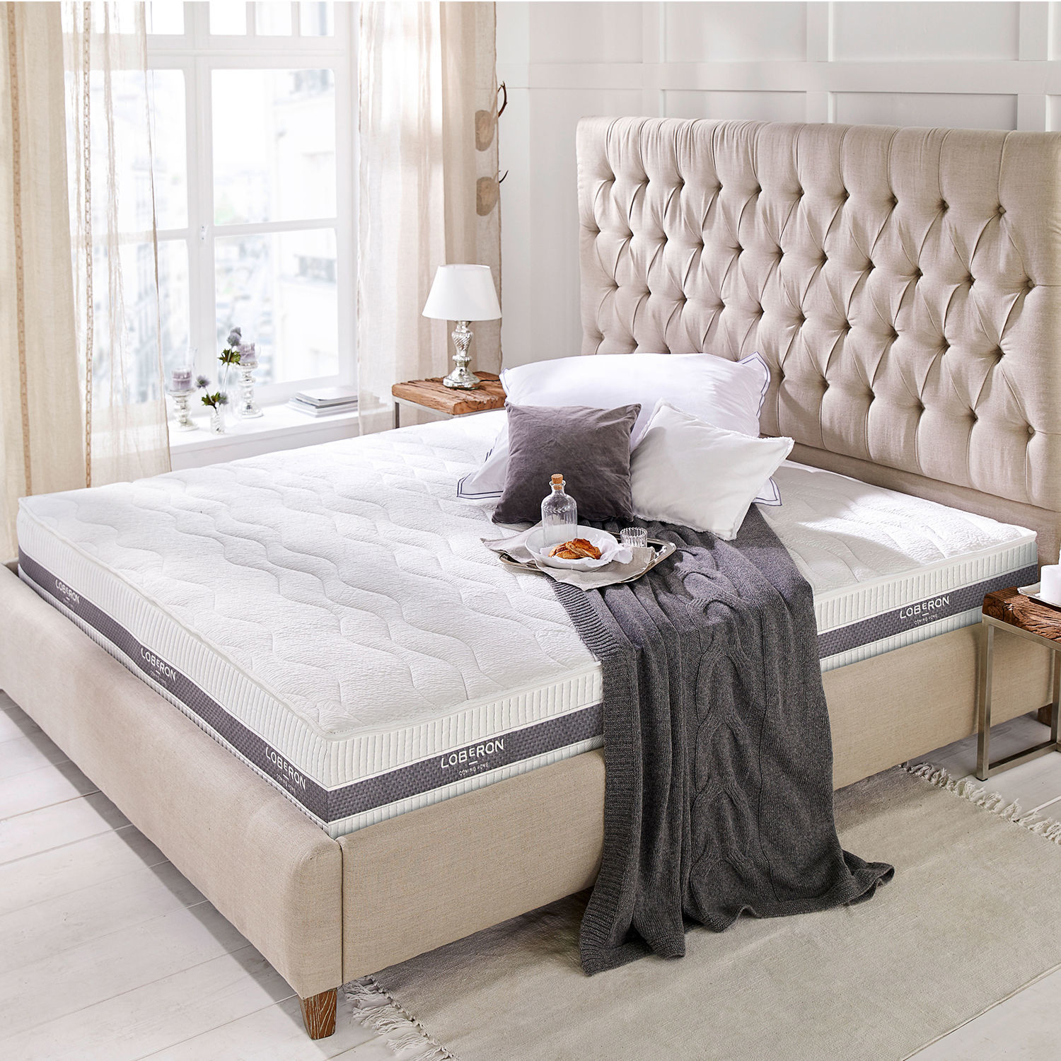Matratze 180x200 Turim Moderne weisse Loberon-Matratze auf beige gepolstertem Bett mit gestepptem Kopfteil im hellen Raum