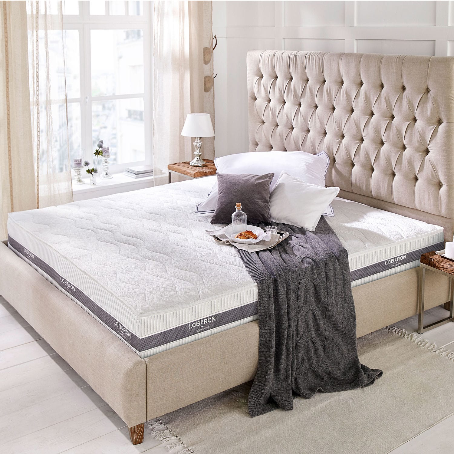 Matratze 180x200 Turim Moderne weisse Loberon-Matratze auf beige gepolstertem Bett mit gestepptem Kopfteil im hellen Raum