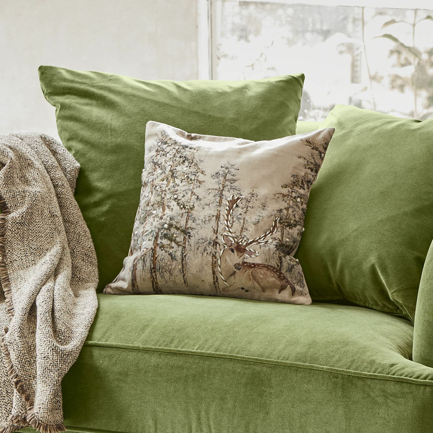 Kissenhülle Valoisin Grünes Samtsofa mit dekorativem Hirschkissen und beigem Plaid für ein gemütliches Wohnzimmer