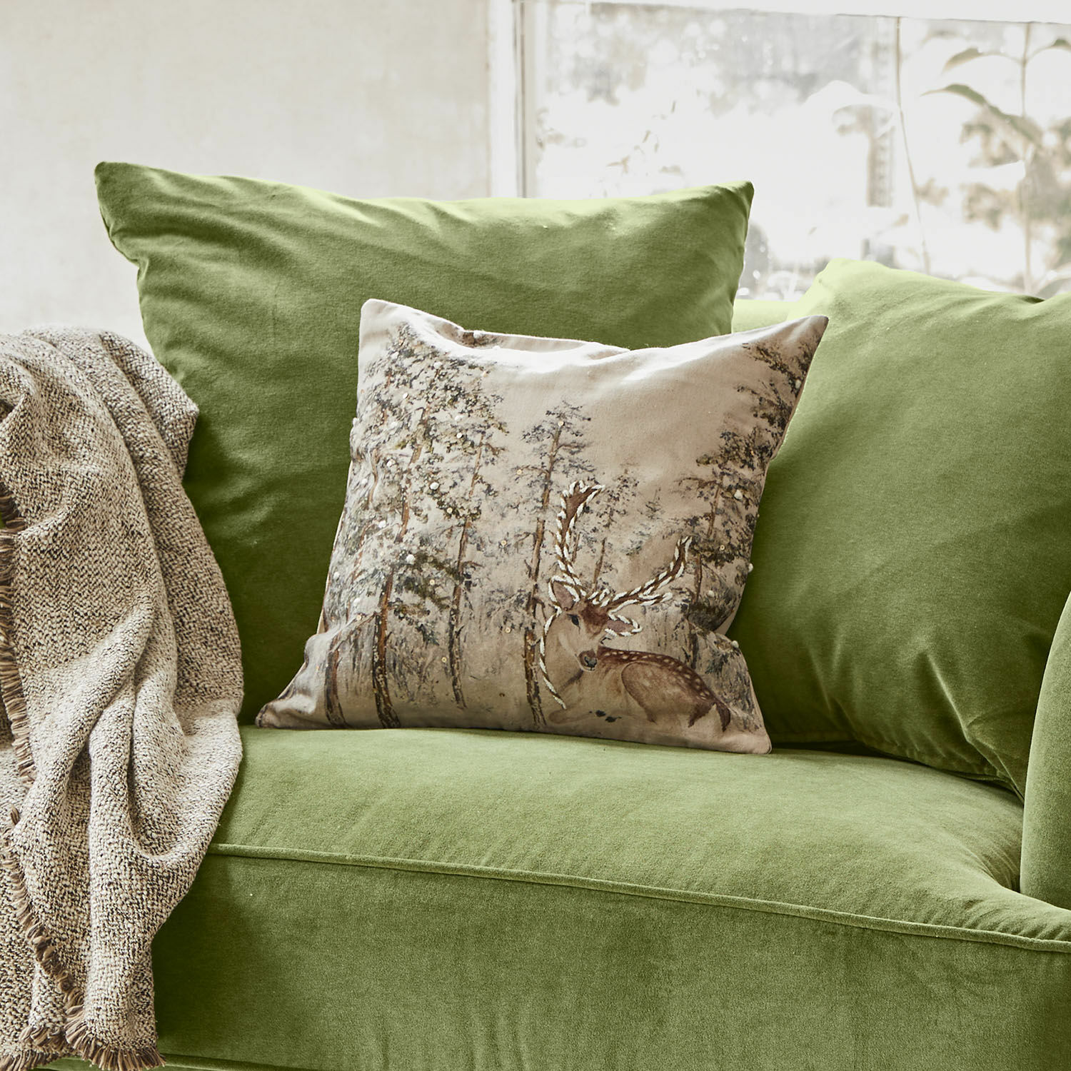 Kissenhülle Valoisin Grünes Samtsofa mit dekorativem Hirschkissen und beigem Plaid für ein gemütliches Wohnzimmer