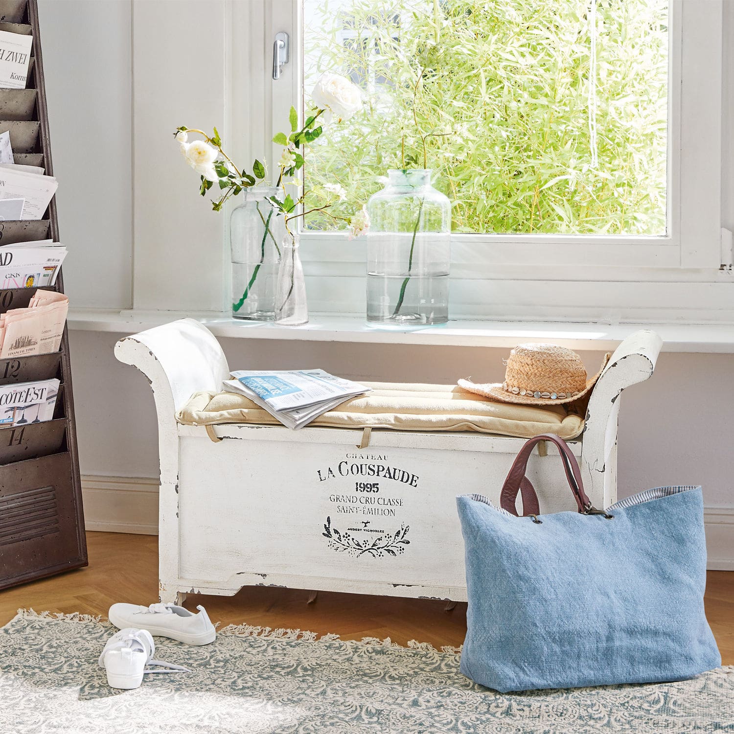 Bank Andance Weisse Holzbank mit Polster, Strohhut und blauer Tasche vor Fenster mit Blumen