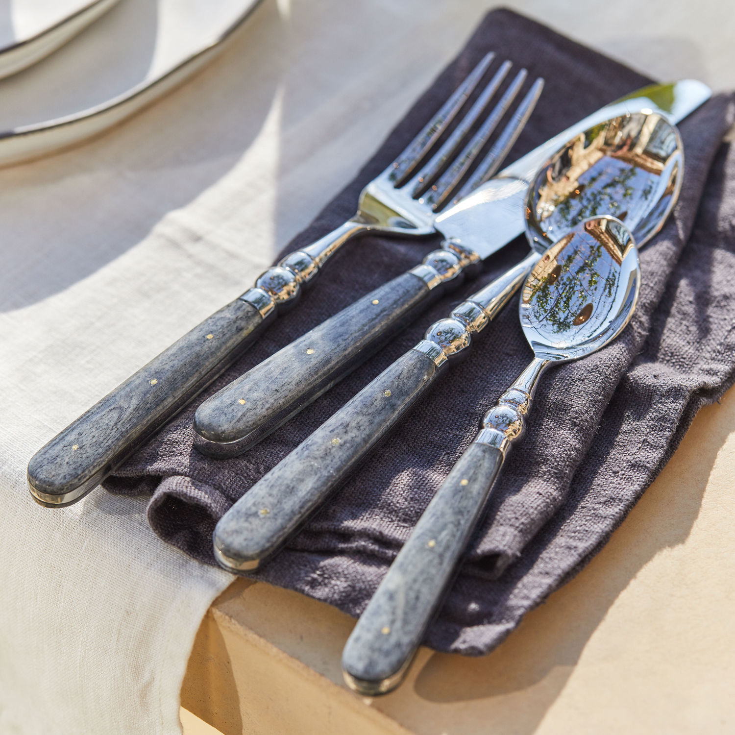 Besteck Bigeste Besteckset mit grauen Marmorgriffen und Metallenden auf dunkler Stoffserviette