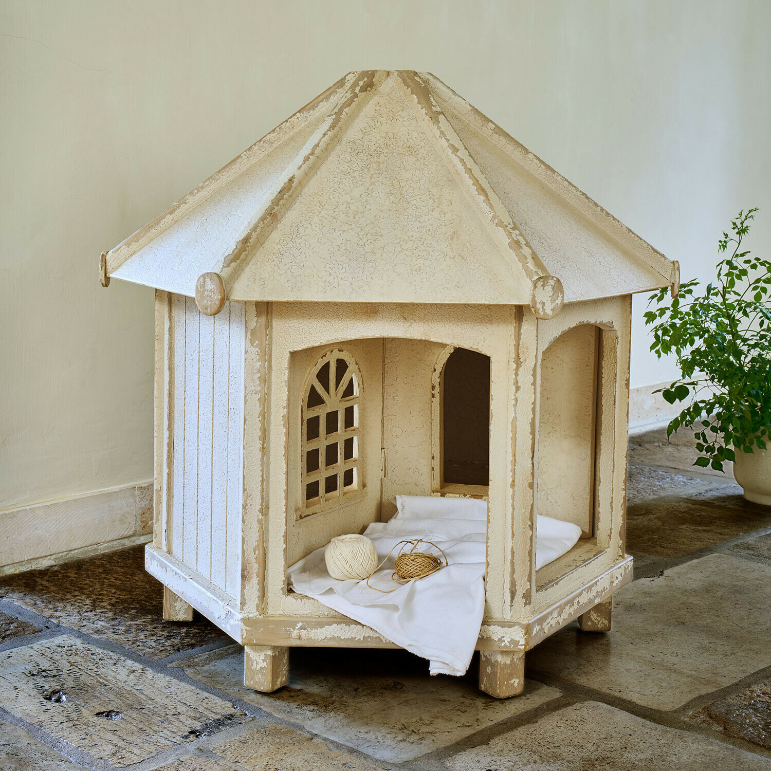 Katzen-Gartenhaus Alvérine Beige hölzernes Katzenhaus mit Fenstern und weissem Kissen auf Steinboden