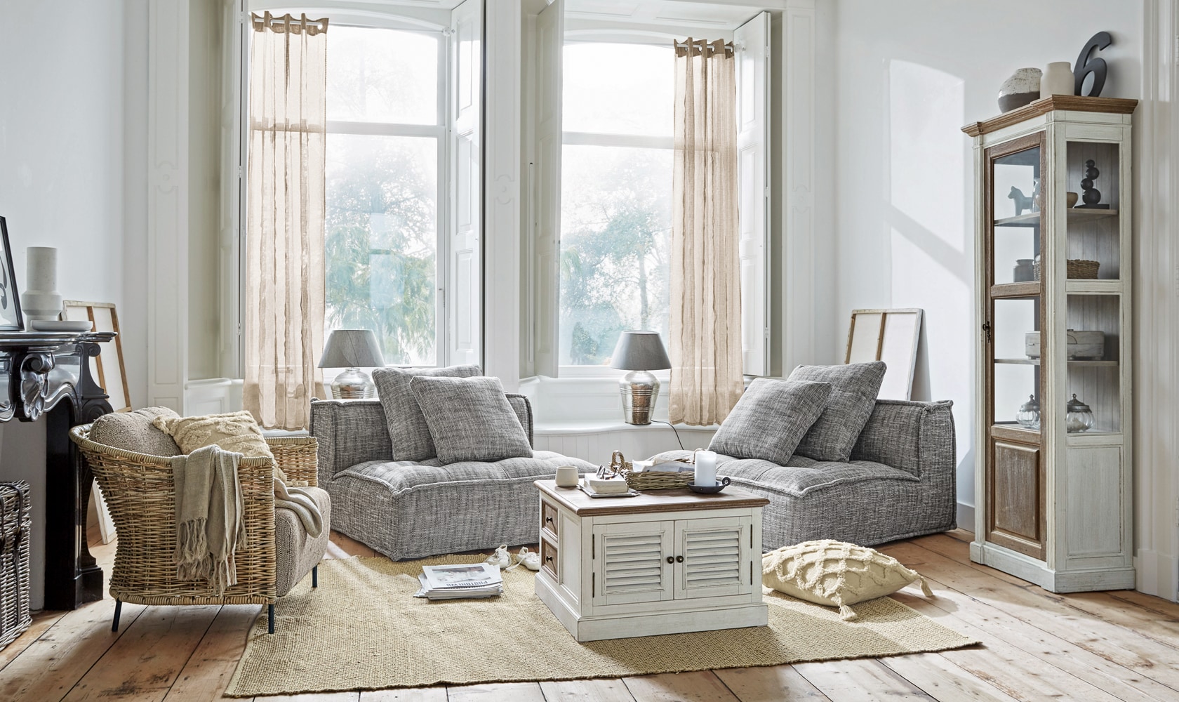 Helles Wohnzimmer mit grauen Sesseln und weissem Holzschrank auf Juteteppich, moderner skandinavischer Stil