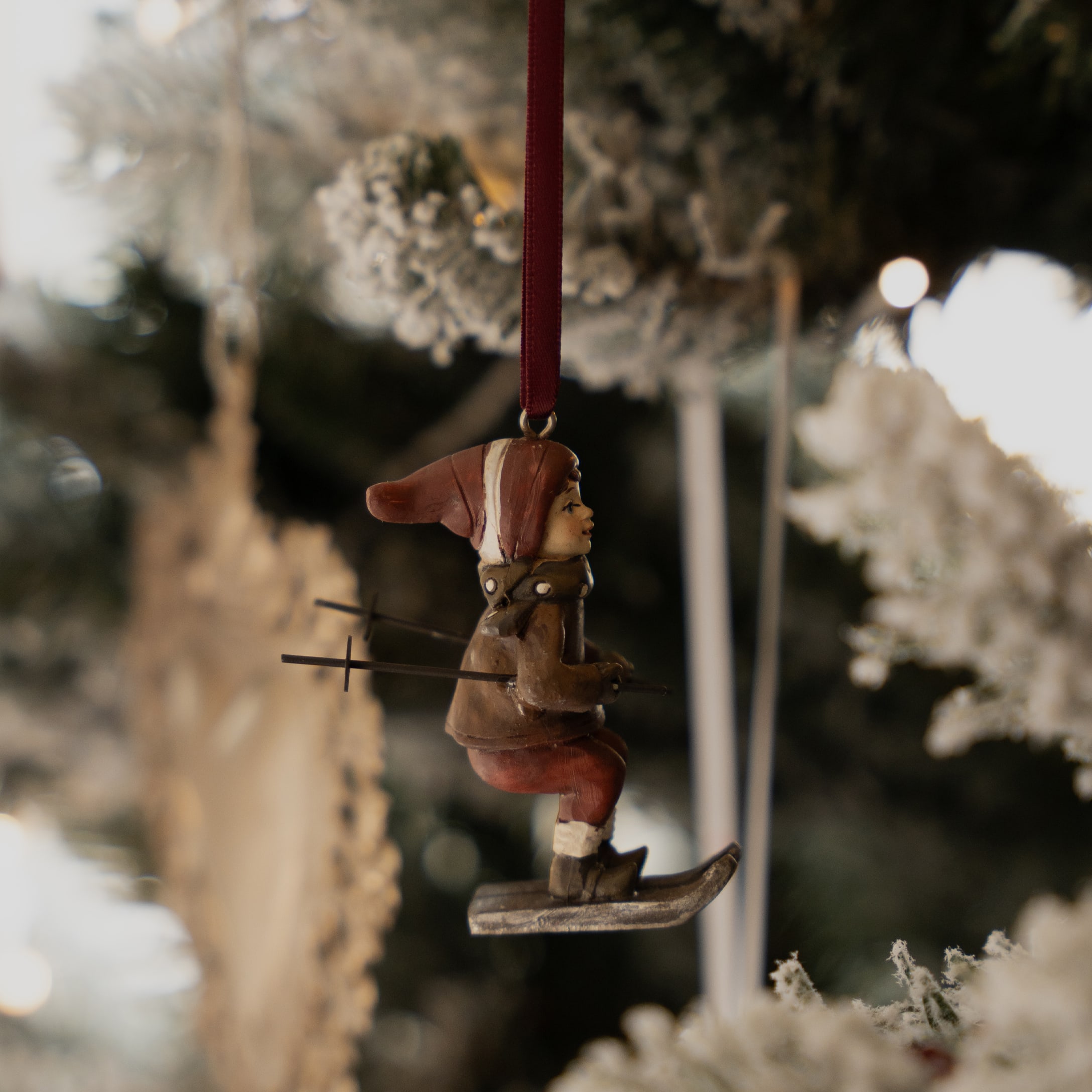 Weihnachtsschmuck mit Skifahrerfigur in brauner Kleidung und roter Mütze am Weihnachtsbaum