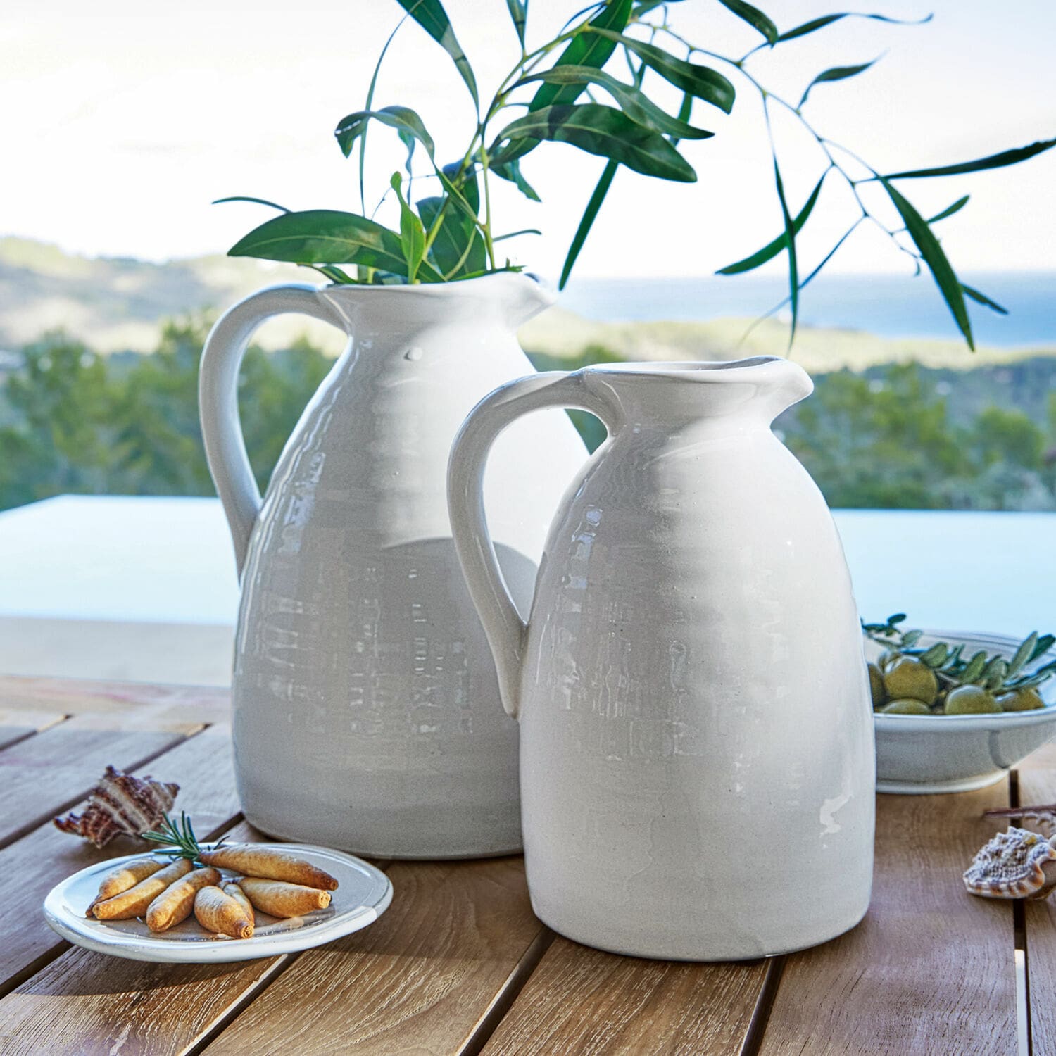 Vase 2er Set Yarick Weisse Keramikkrüge auf Holztisch mit grünen Blättern und Snacks, Tischdekoration