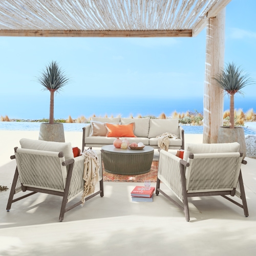 Outdoor-Möbelset mit beigen Polstern und Holzrahmen auf Terrasse mit Meerblick unter Pergola