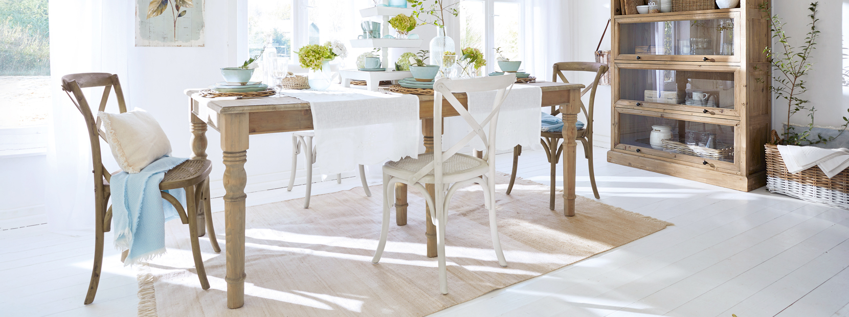 Helle Landhaus-Esszimmer mit Holztisch, gemischten Stühlen und natürlichen Dekorationen in Weiss und Beige