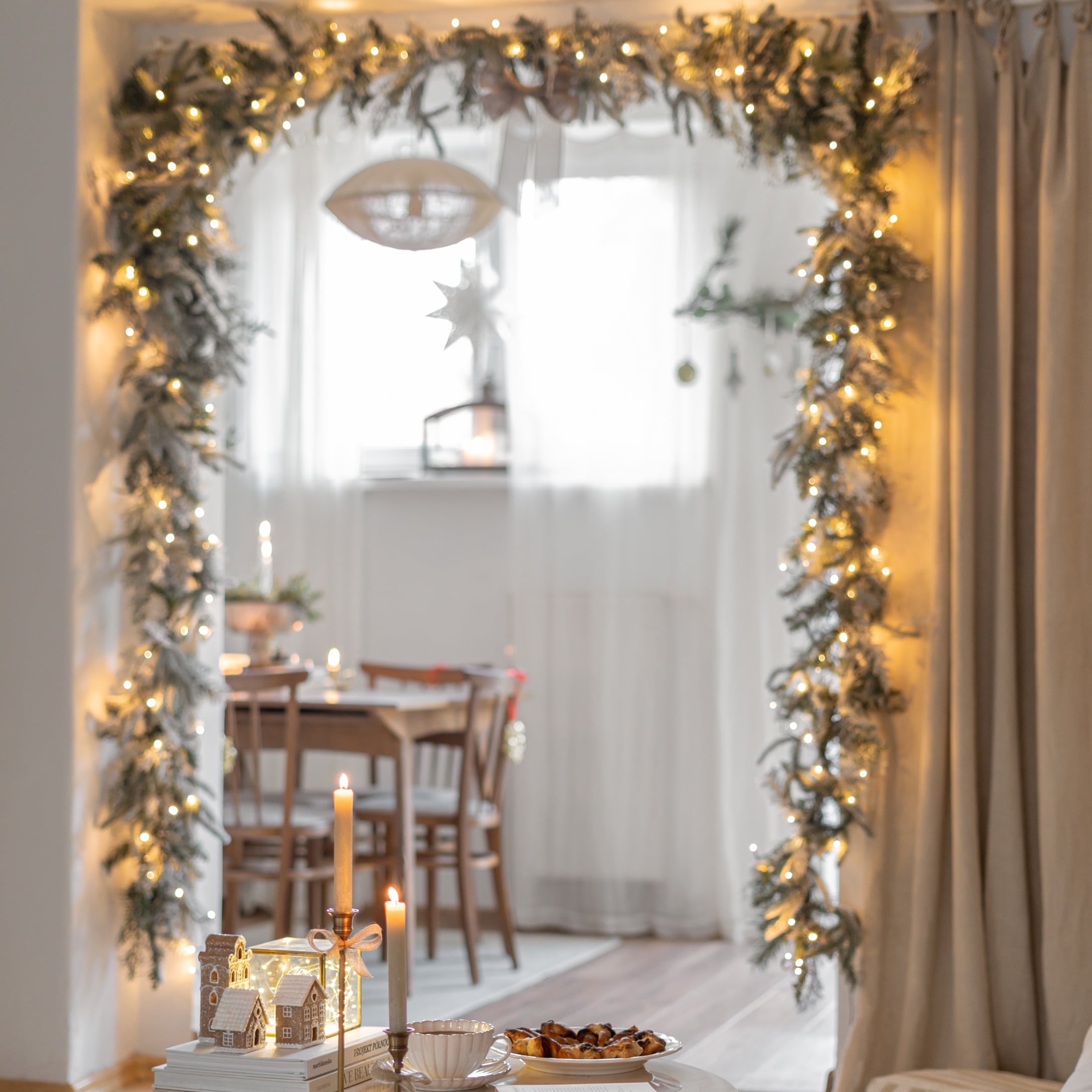 Weihnachtliche Dekoration mit Lichterkette und Kerzen in einem gemütlichen Raum mit Holztisch