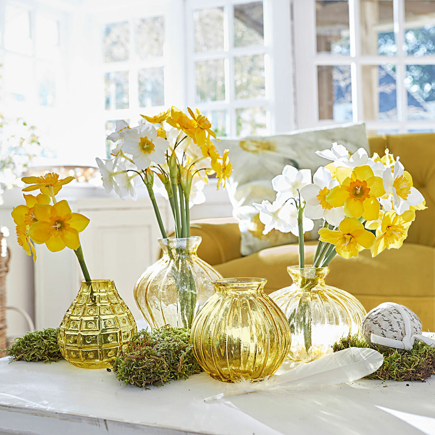 Deko-Blume 12er Set Misapina Set aus gelben Glasvasen mit gelb-weissen Blumen auf weissem Tisch in hellem Raum
