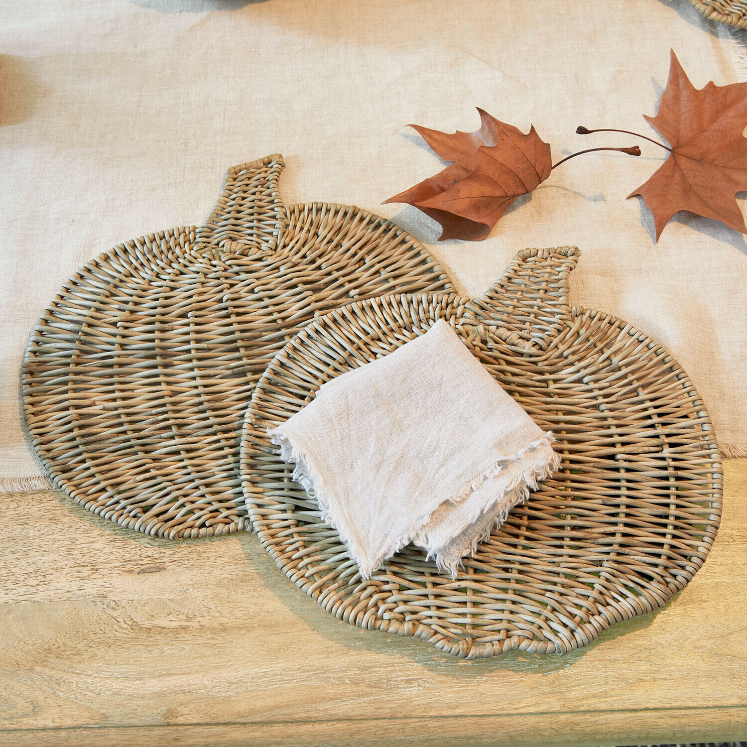 Platzset 2er Set Larivonne Zwei naturfarbene Kürbisförmige Rattan-Untersetzer mit Leinenserviette und Herbstblättern