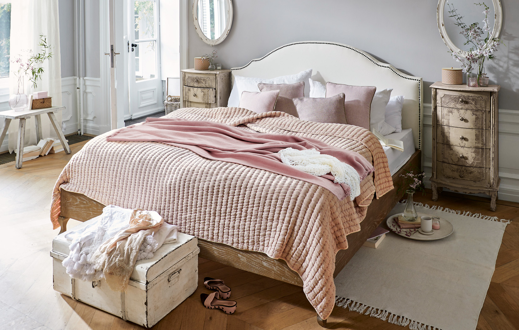 Gemütliches Shabby-Chic-Schlafzimmer mit rosa Bettdecke und Vintage-Holzmöbeln im Landhausstil