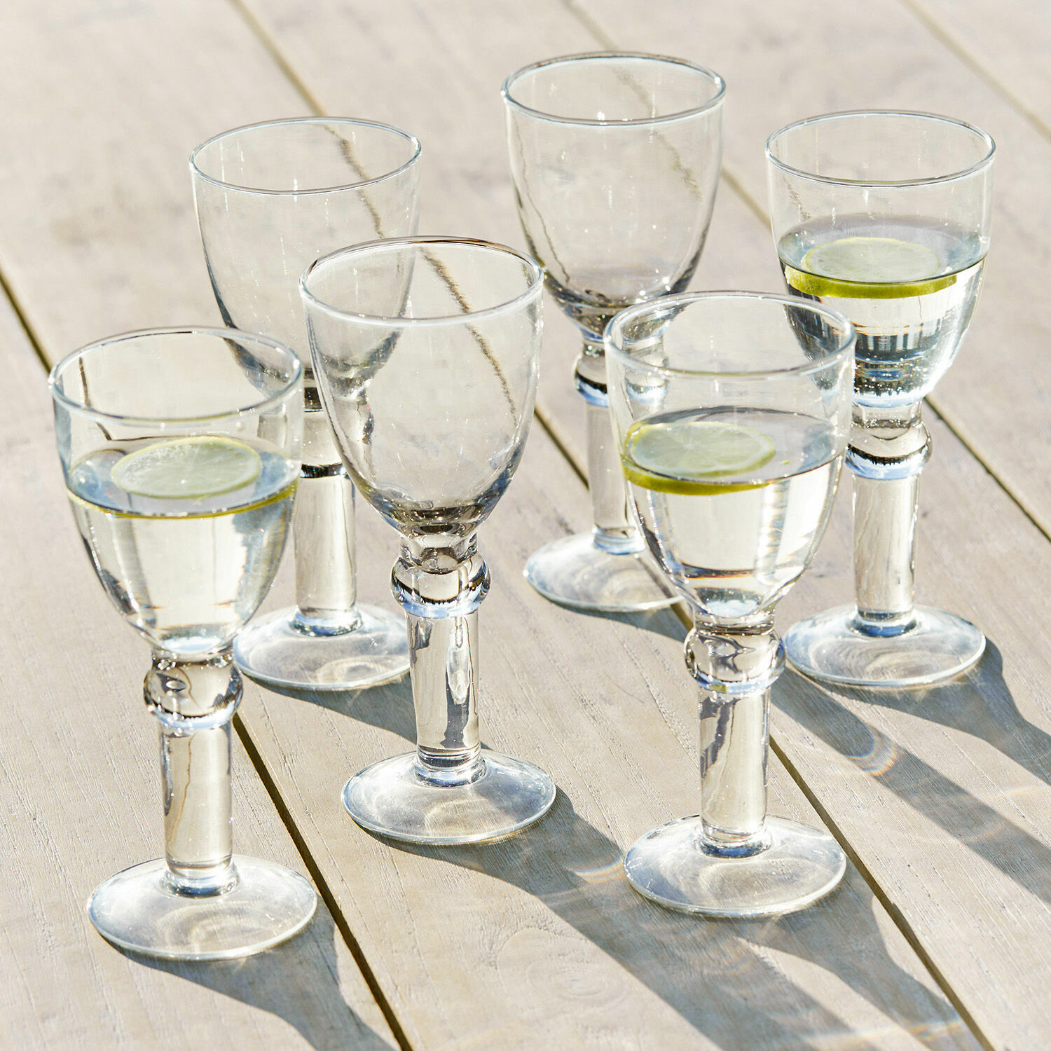 Weinglas 6er Set Devon Sechser-Set klare Gläser mit Wasser und Zitronenscheiben auf hellem Holztisch