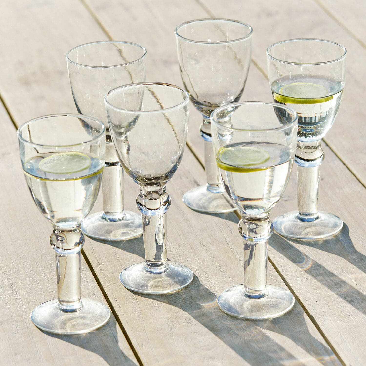 Weinglas 6er Set Devon Sechser-Set klare Gläser mit Wasser und Zitronenscheiben auf hellem Holztisch