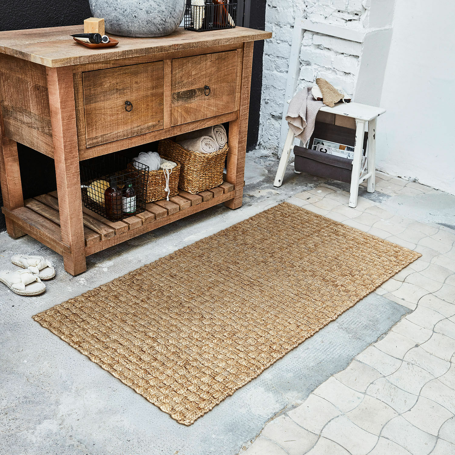Läufer Daoukro Beiger Teppich aus natürlicher Jute auf dem Boden neben einer Holzkommode und einem weissen Hocker