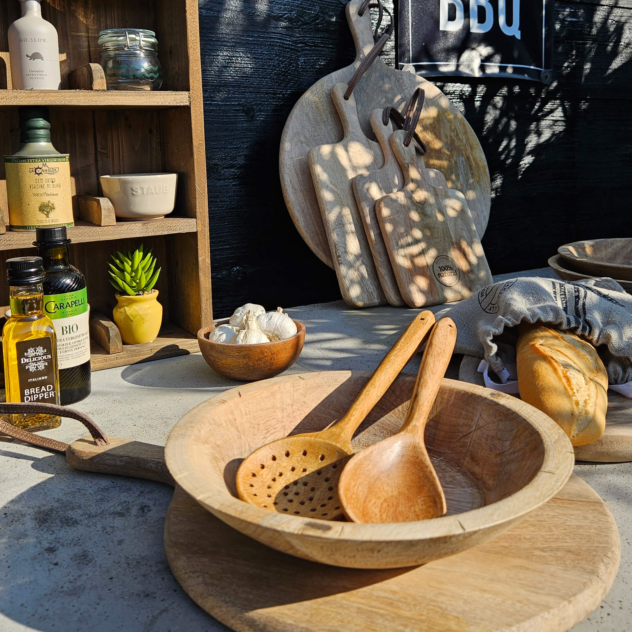 Set aus Holzschneidebrettern und Kochlöffeln auf Tisch mit Brot und Olivenöl