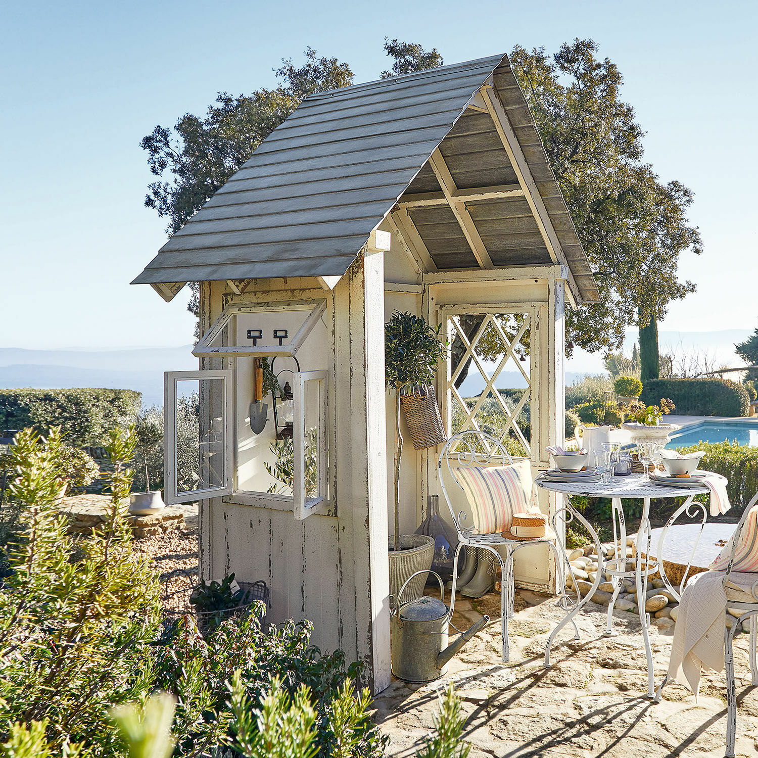 Gartenhaus Sumter Weisse Holz-Gartenlaube mit Metalltisch und Stühlen auf Steinboden neben dem Pool
