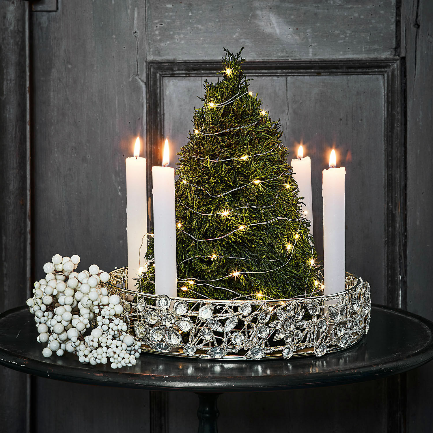 Deko-Baum Moran Dekorativer Kerzenhalter mit weissen Kerzen und grünem Tannenbaum mit LED-Lichterkette auf schwarzem Tisch