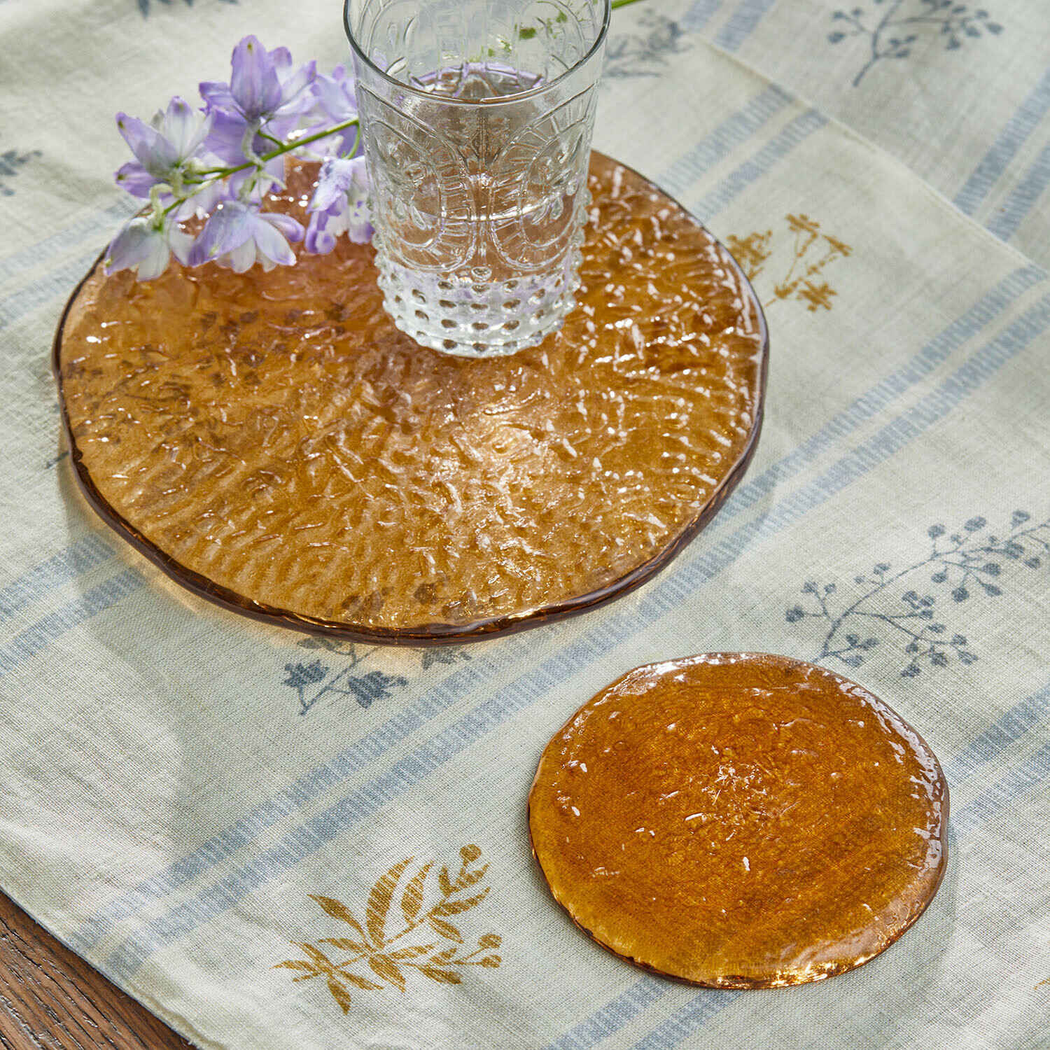 Untersetzer 2er Set Montelisse Transparentes Glas auf orangefarbenem Glasuntersetzer mit Blume auf Leinentischdecke
