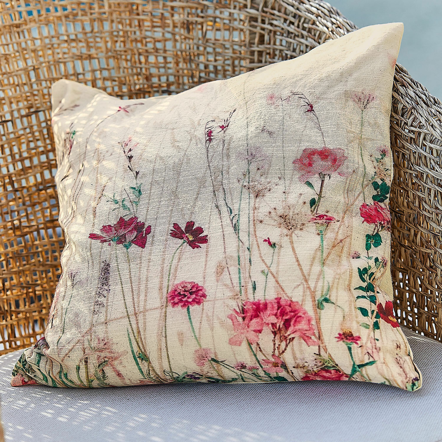 Kissenhülle Briovene Beiges Kissen aus Naturstoff mit Blumenmuster auf einem Korbsessel, dekoratives Wohnaccessoire