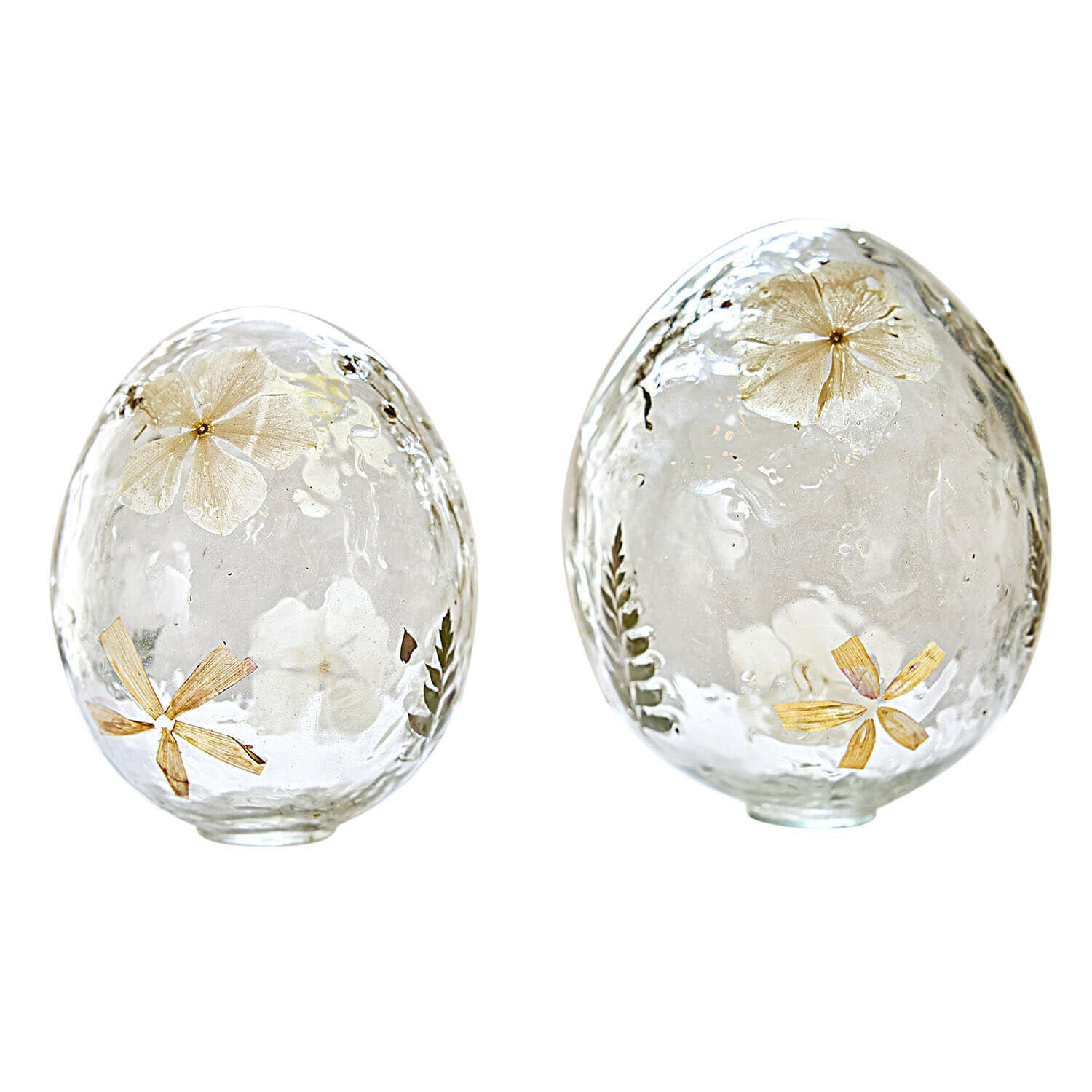 Zwei transparente Glaseier mit getrockneten Blumen und Blättern als Frühlingsdekoration