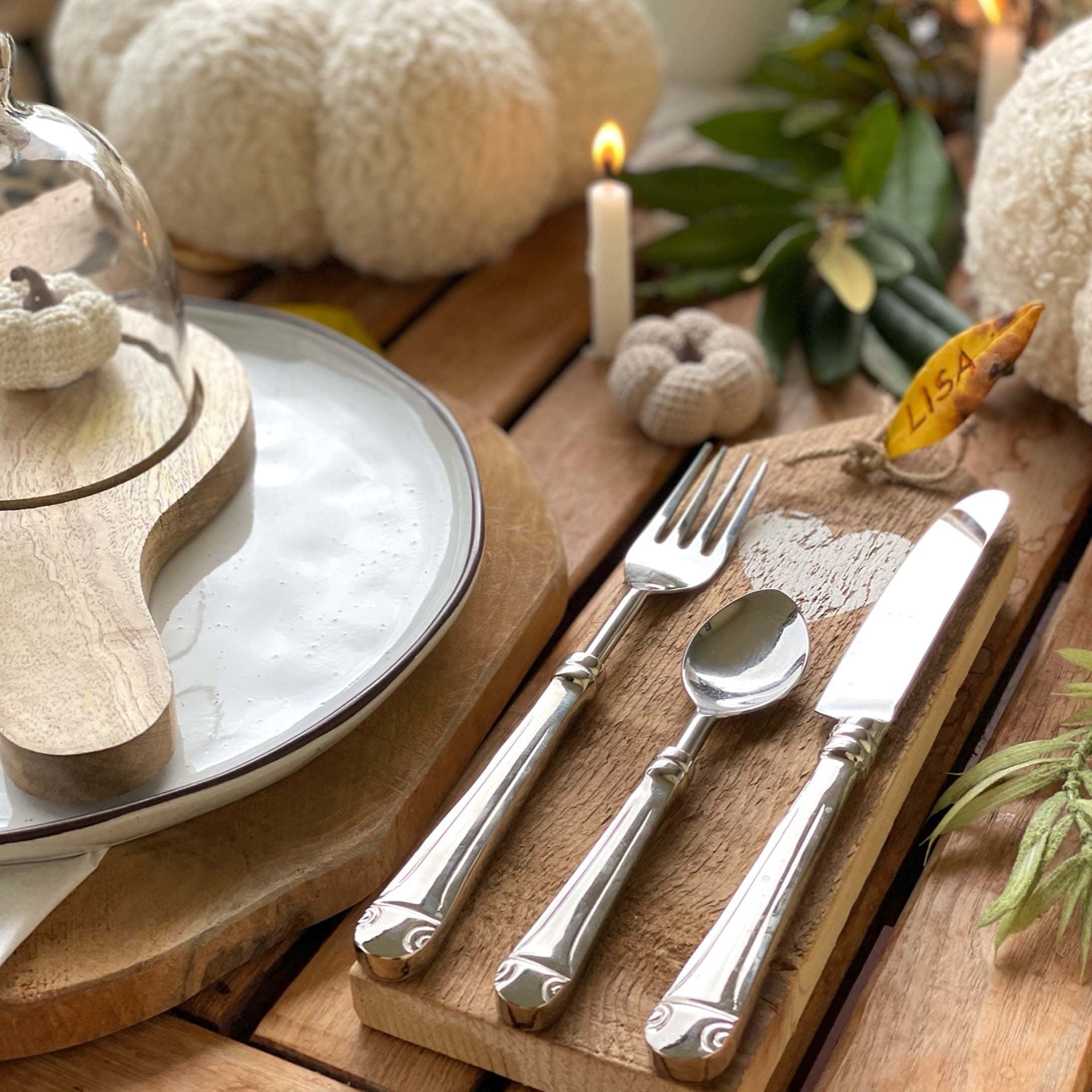 Rustikaler Holztisch mit herbstlicher Dekoration, silbernem Besteck und weissen gehäkelten Kürbissen