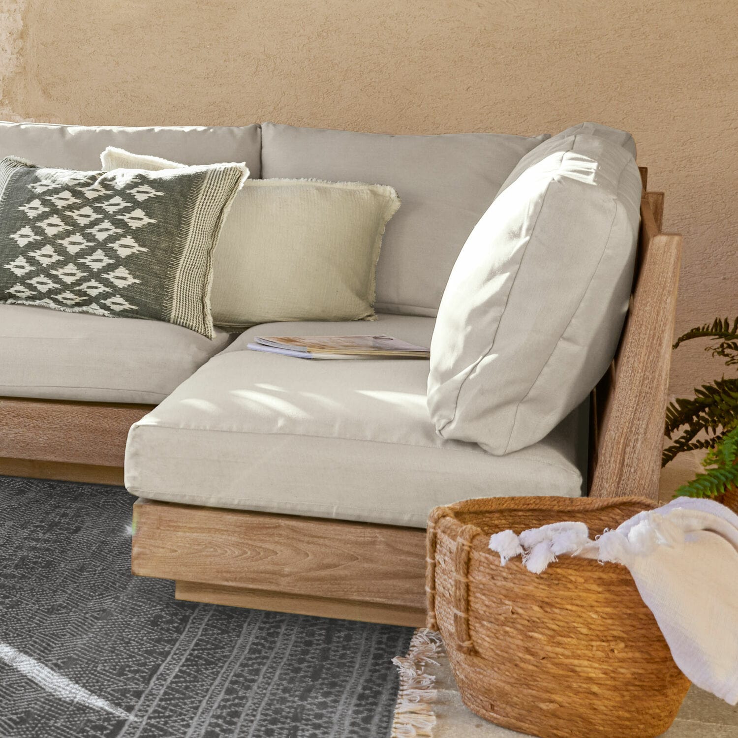 Sofaelement Courtelevant Ecksofa mit hellgrauem Stoffbezug und Holzrahmen, dekorativem Kissen und Korb mit Stoffdecke