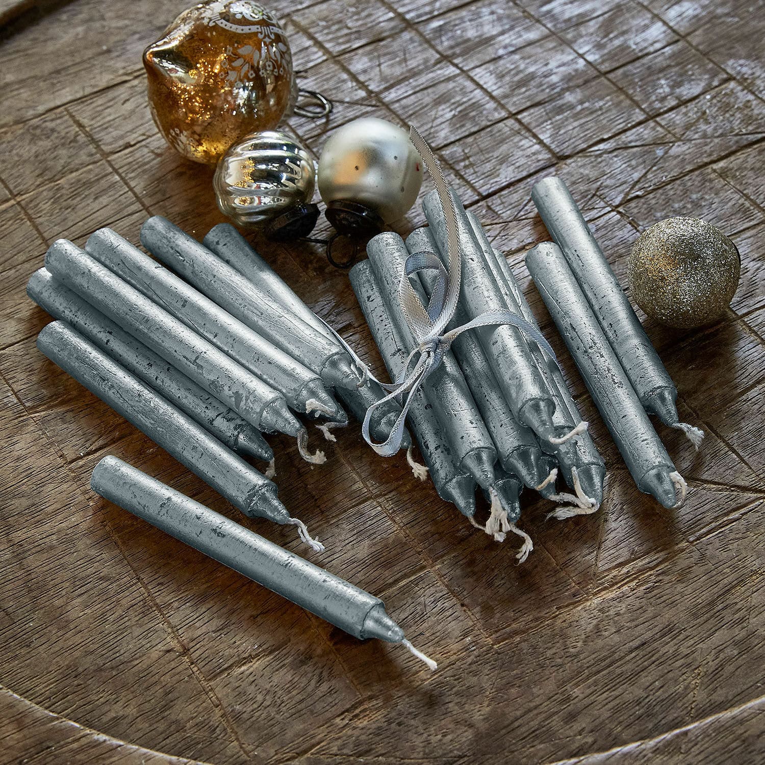 Kerze 12er Set Bauceau Set aus silbernen Metall-Tischkerzen auf Holztisch mit goldenen Weihnachtskugeln als Dekoration