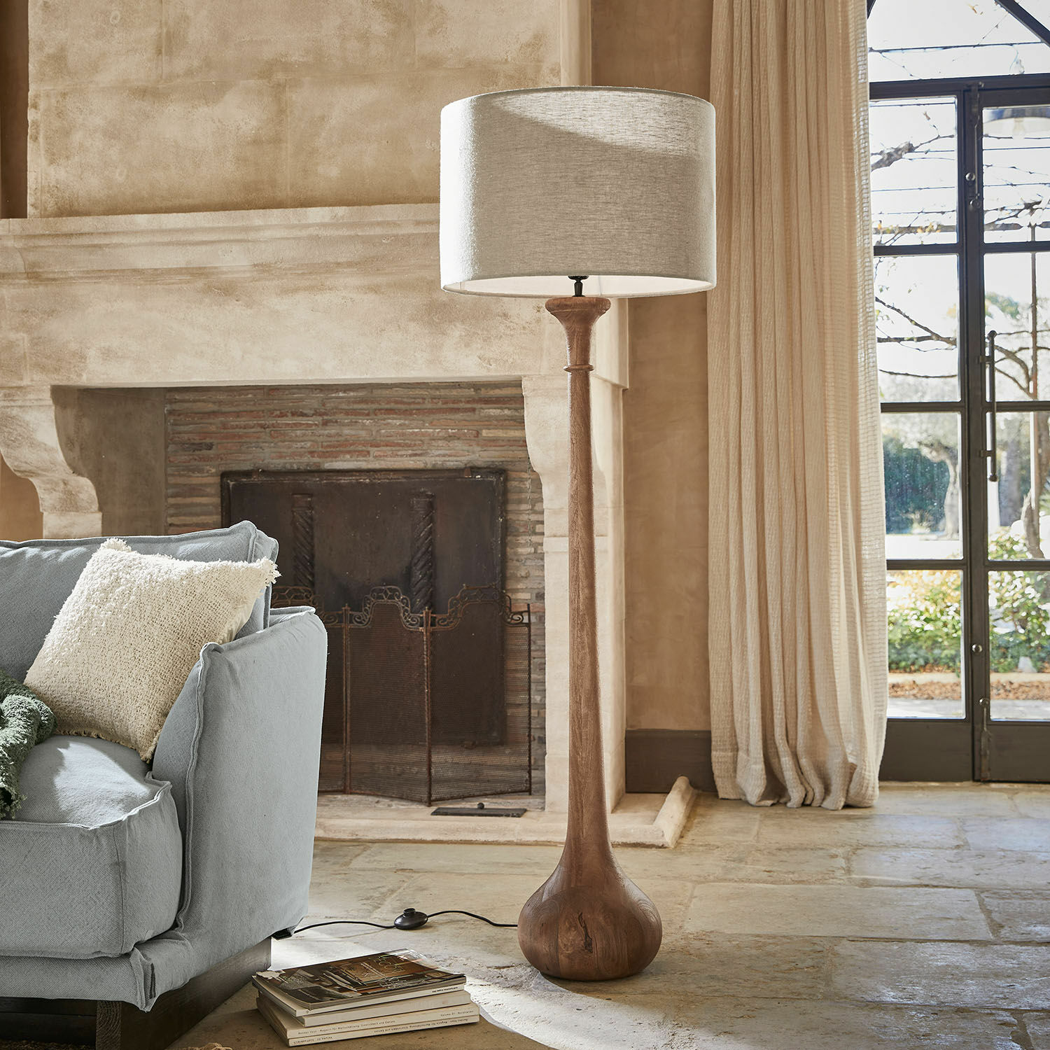 Stehlampe Andrées Stehlampe mit Holzfuss und beigem Lampenschirm in gemütlichem Wohnzimmer mit Cheminée