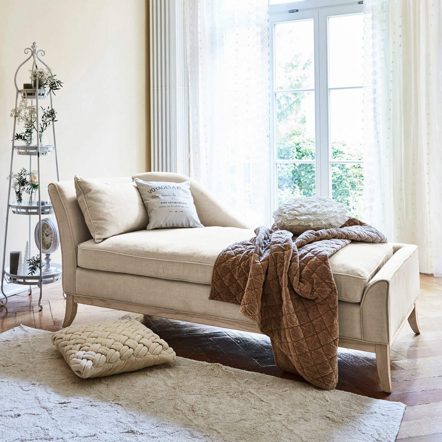 Chaiselongue Alphonse Beige Chaiselongue aus Stoff mit Kissen und brauner Decke in hellem Wohnzimmer