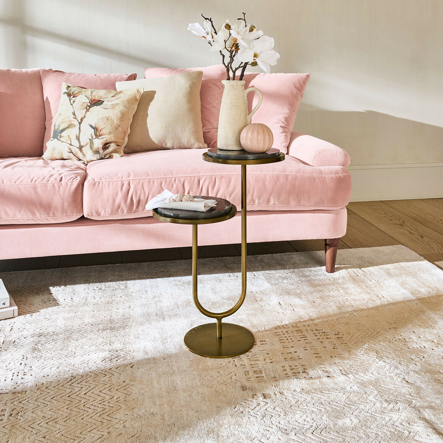 Doppelter Beistelltisch mit Metallgestell und Marmorplatten vor rosa Sofa im Wohnzimmer