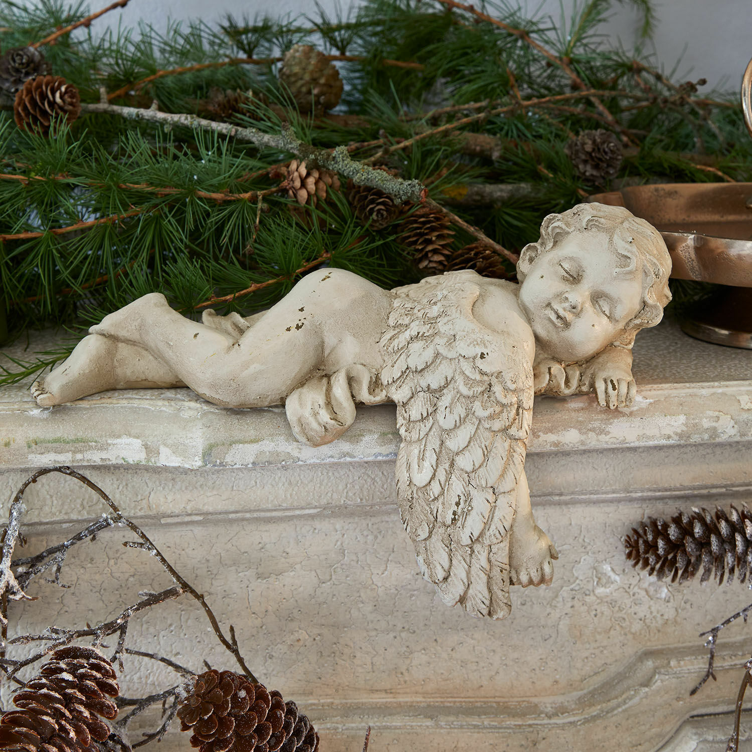Deko-Engel Deronza Betonfigur eines cremefarbenen Engels auf Kaminsims mit Tannenzweigen und Zapfen, Weihnachtsdekoration